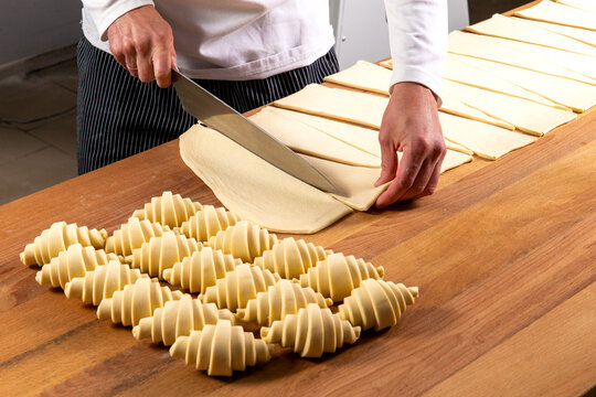 Pastry chef cutting puff pastry for croissants. - Powered by Adobe