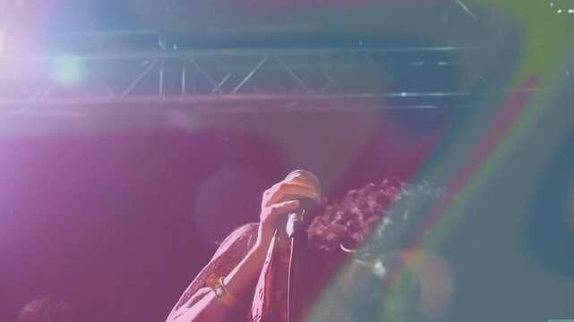 Singer on mic stand singing, flipping hair under colored lights boosting show energy