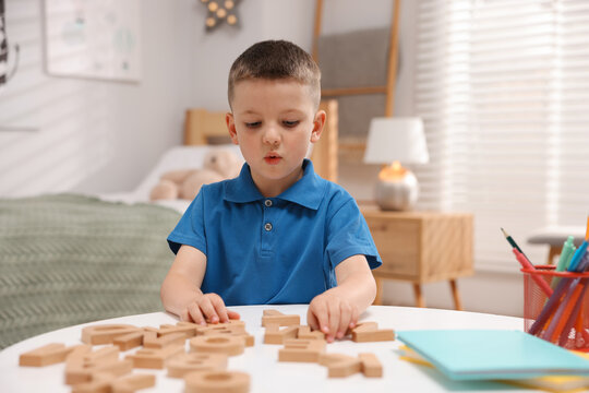 Dyslexia. Little boy learning letters at table indoors
