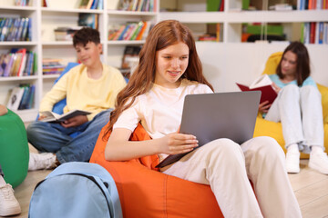 Student with laptop studying on bean bag in library