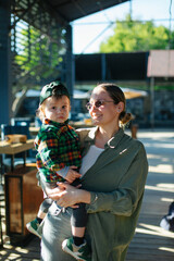 Fototapeta premium Mom and her son toddler in the park. Mom is hugging her baby, they are walking outdoor. Happy family dream concept. Mother and child together, lifestyle photo. 