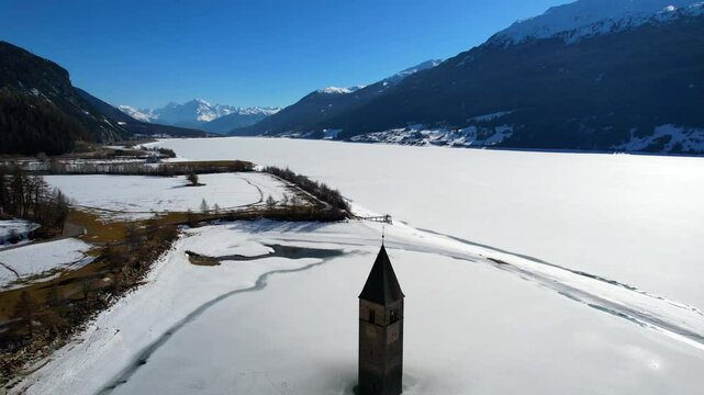 Church tower of Reschen - Vinschgau, South Tyrol - Aerial view over the tower with a view of the Ortler Berga massif and the frozen Lake Rechen