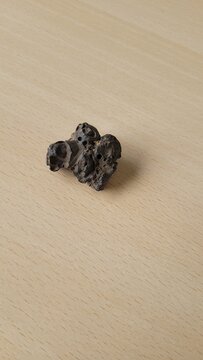 pierre &eacute;trange similaire &agrave; une m&eacute;t&eacute;orite sur table en bois