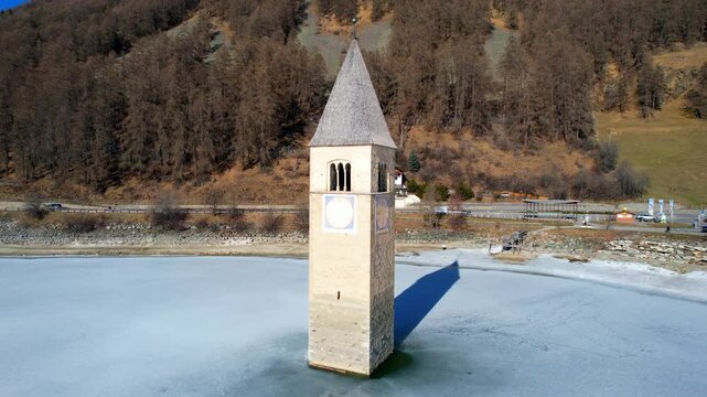 Church tower of Reschen - Vinschgau, South Tyrol - left-turning aerial view over the frozen lake