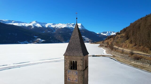Church tower of Reschen - Vinschgau, South Tyrol - reverse aerial view of the tower with a view of the frozen Lake Rechen