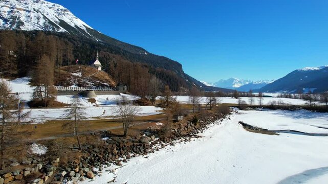 Church tower of Reschen - Vinschgau, South Tyrol - rotating panoramic aerial view from the village to the tower with a view of the frozen Lake Rechen