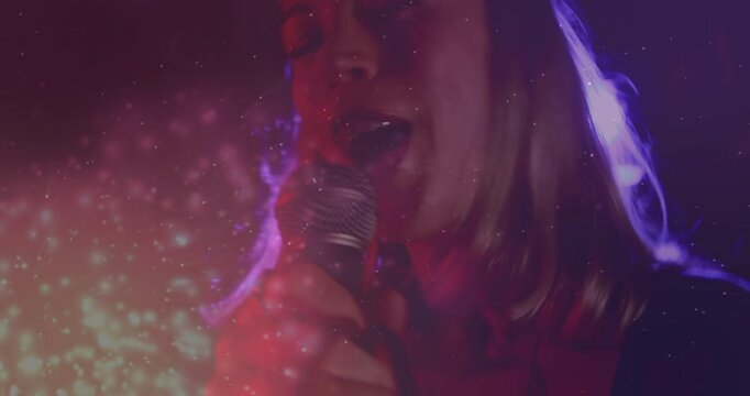 Singer pressing mic under moody lights while camera panning cymbal, keyboard for emotive music set
