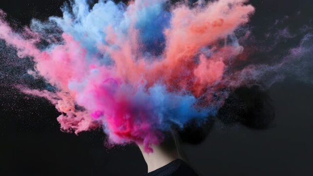 A young woman with dark hair has colorful powder exploding around her head, creating a vibrant and artistic effect. 