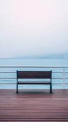Empty bench faces foggy cityscape and calm water on wooden dock pier