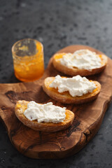 Ciabatta slices with orange marmalade and ricotta on olive board