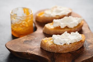 Ciabatta slices with orange marmalade and ricotta on olive board