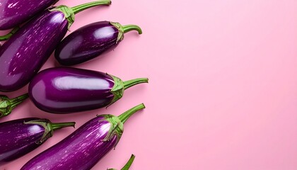 Purple eggplants arranged on the left side of a pink background