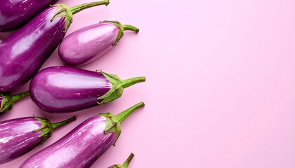 Purple eggplants arranged on the left side of a pink background