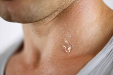 Fototapeta premium Close up of male neck with summer sweat drop on collarbone, showing skin texture and moisture, evoking fresh and natural feeling in warm environment