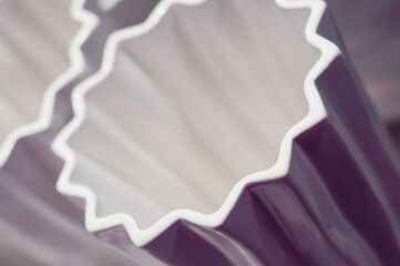 Abstract close-up of a purple ceramic vase with a distinctive wavy white edge, creating a modern...
