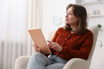Woman with modern tablet in armchair at home