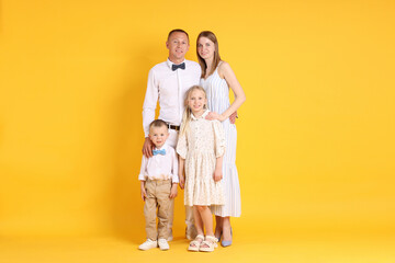 Full length portrait of happy family on yellow background