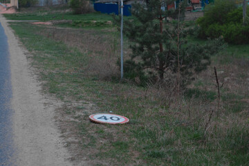 dirt road with 40 kmh speed limit and warning sign lies on the ground