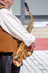 musician playing a golden alto saxophone outdoors