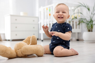 Naklejka premium Cute little baby playing with teddy bear in room