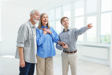 Smiling real estate agent showing apartment to couple indoors