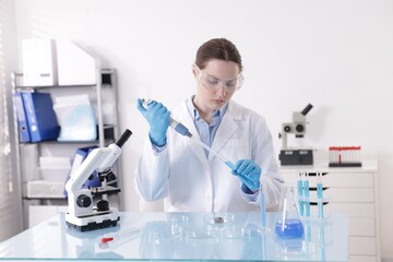Scientist working with sample in Petri dish at table in laboratory