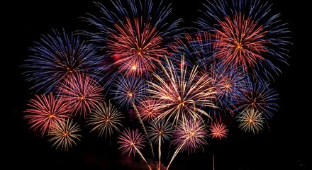 Vibrant Fireworks Display Against a Dark Night Sky, Bursting with Red, Blue, and Gold Colors