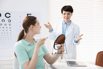 Fototapeta premium Ophthalmologist teaching patient to use contact lenses at table in office