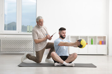 Obraz premium Doctor and patient exercising with medicine ball in clinic