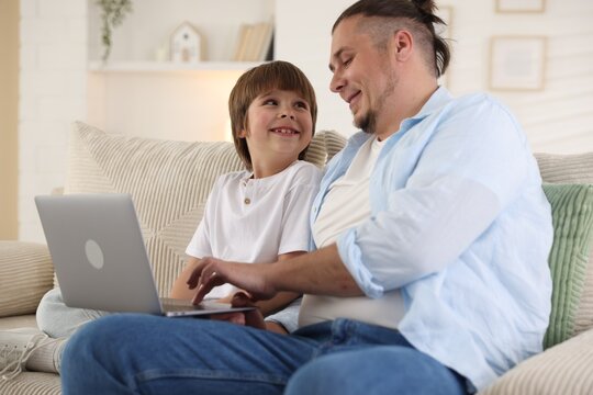 Father and his son watching something on laptop at home