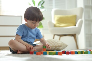 Cute little child playing with colorful cubes at home. Space for text