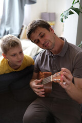Father teaching his son to play ukulele