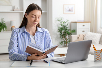 Woman with book learning at table indoors. Self-study