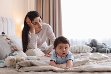 Fototapeta premium Woman suffering from postpartum depression with her little baby on bed at home. Space for text