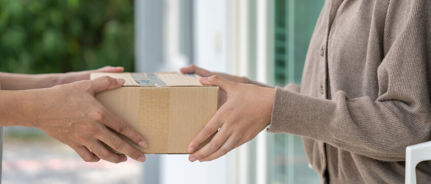 Happy smiling woman receives boxes parcel from courier in front house. Delivery man send deliver express. online shopping, paper containers, takeaway, postman, delivery service, packages