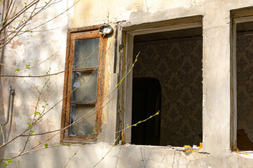 Close-up of broken window and open frame on an old abandoned building with peeling wall and visible...