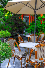 Outdoor cafe with rattan furniture and umbrella in lush garden setting