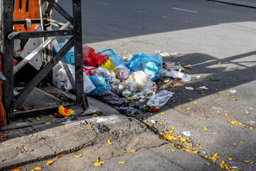 Urban street litter: plastic bags, bottles, and trash on city pavement