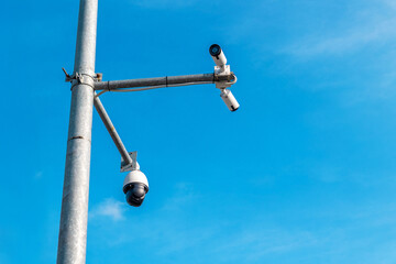 Fototapeta premium Security cameras mounted on pole against clear blue sky for surveillance