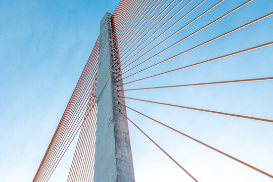 Modern cable-stayed bridge with blue sky and red cables in daylight - Powered by Adobe