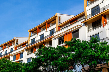 Modern residential building with orange accents and lush greenery