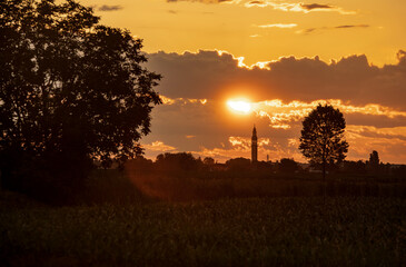 Golden sunset illuminating countryside landscape with bell tower silhouette