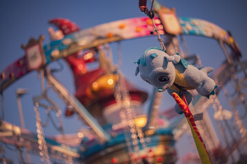 Plush dragon toy hanging from a carousel at chioggia, italy, during sunset