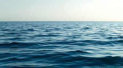 A tranquil blue ocean stretches to the horizon under a clear sky, its gentle waves creating a peaceful seascape