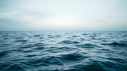 A tranquil blue ocean stretches to the horizon under a cloudy sky, its gentle waves creating a peaceful seascape
