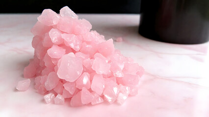 Crushed rose quartz crystals on pink marble texture, wellness background for spa websites or crystal healing Instagram posts