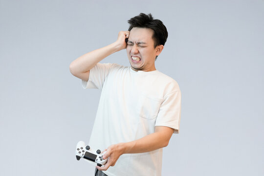 frustrated young asian man play and holding controller
