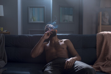 Lonely African American man smokes trying to reduce negative emotions at home