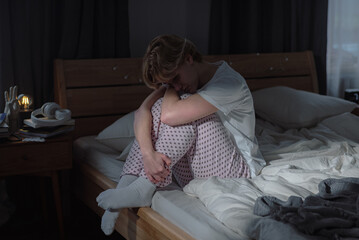 Sadness loneliness and mental health challenges consume young woman sitting on bed