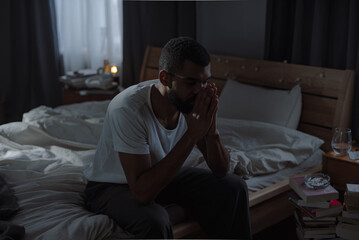 African American man hides face behind palms suffering from obsessive thoughts at home